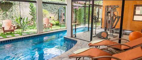 Alberca techada, alberca al aire libre y sombrillas en la alberca