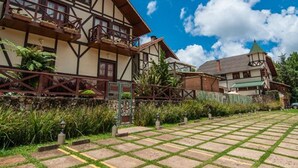 Un edificio tradicional con entramado de madera, un balcón, un sendero de piedra y una pequeña torre.