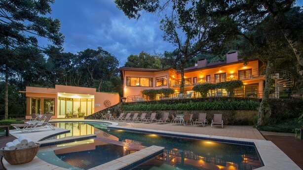 Una casa moderna con piscina, mobiliario exterior y una escalera que lleva a un balcón.