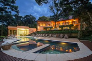 A modern house with a swimming pool, outdoor seating, and a staircase leading to a balcony. - Kuriuwa Hotel (Camanducaia)