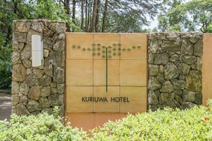 Señal para el Hotel Kuriowa, con una pared de piedra y un panel de madera.