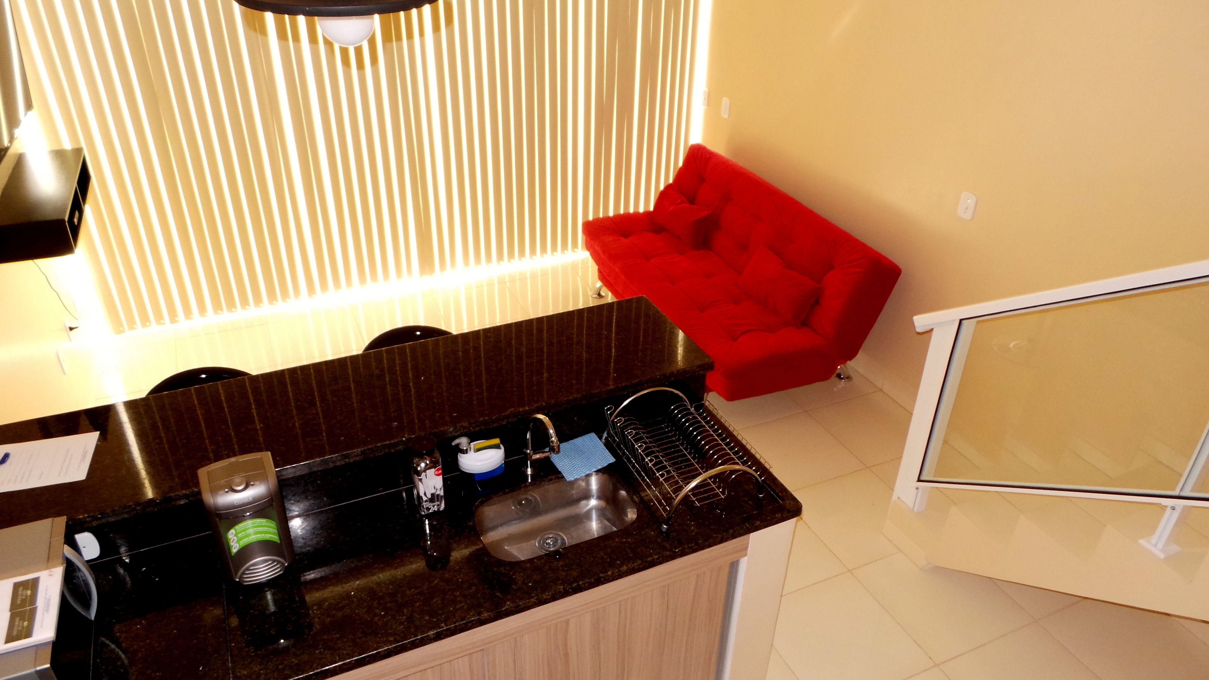 Una cocina con encimera oscura, un fregadero y una silla roja.