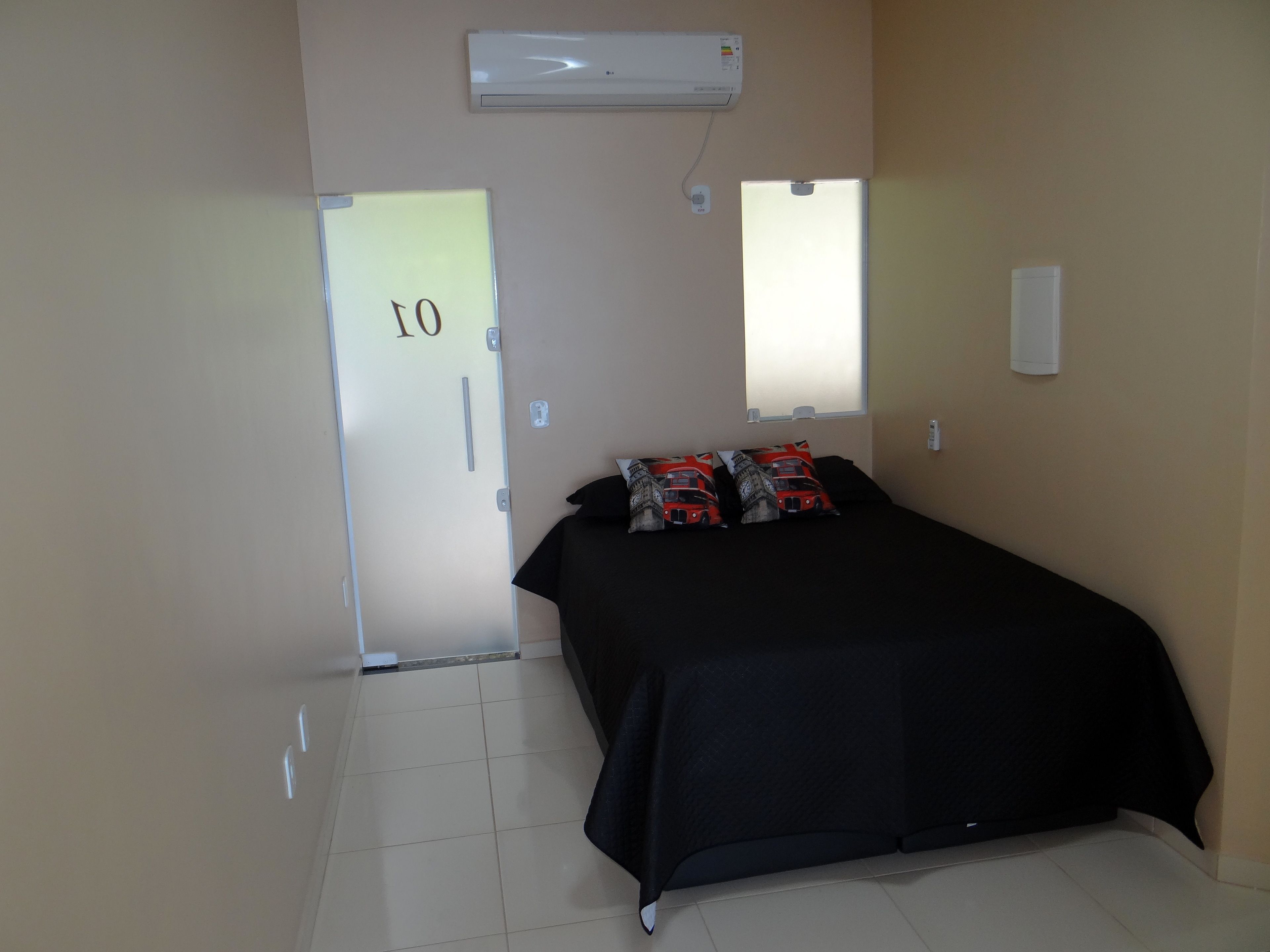 Una habitación con una cama, una puerta con el número 10, un aire acondicionado y una ventana.