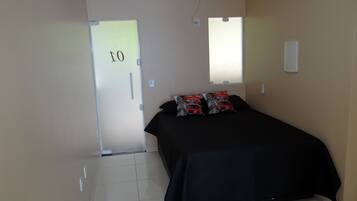 A room with a bed, a door marked "10", an air conditioner, and a window.