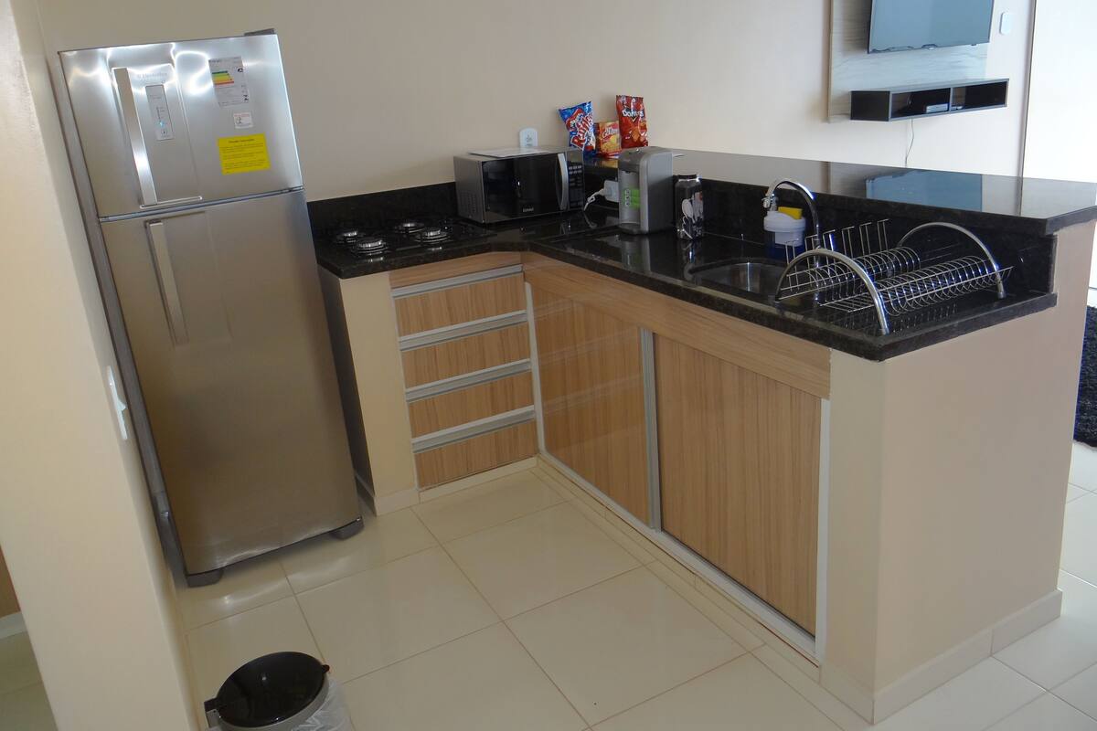 A compact kitchen with a refrigerator, microwave, stove, and sink.
