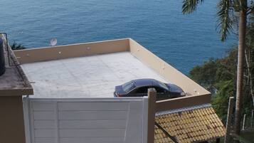 A rooftop terrace with a car parked on it, overlooking the sea.