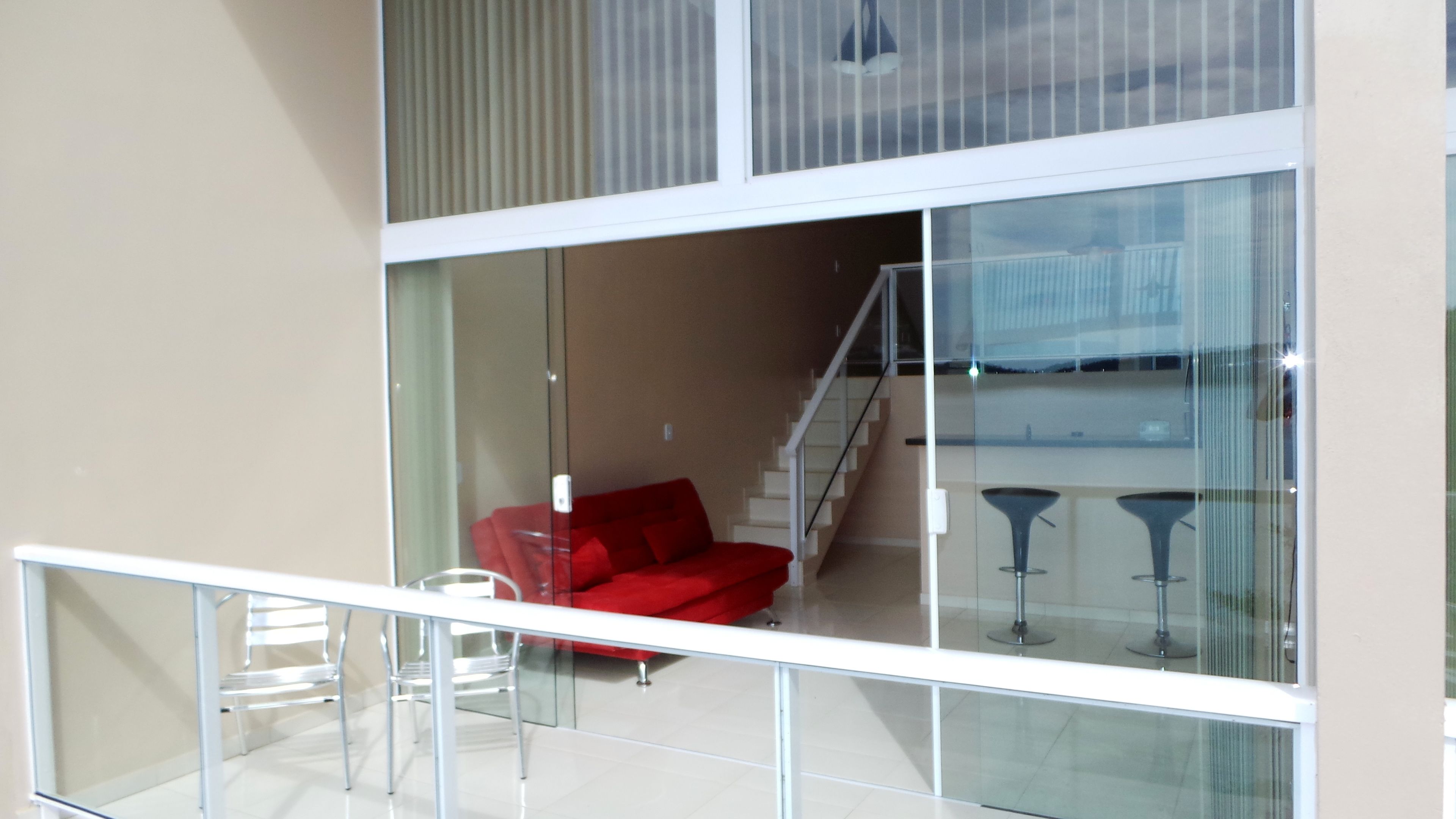 A modern interior with a red sofa, a glass railing, and a staircase leading to an upper level.