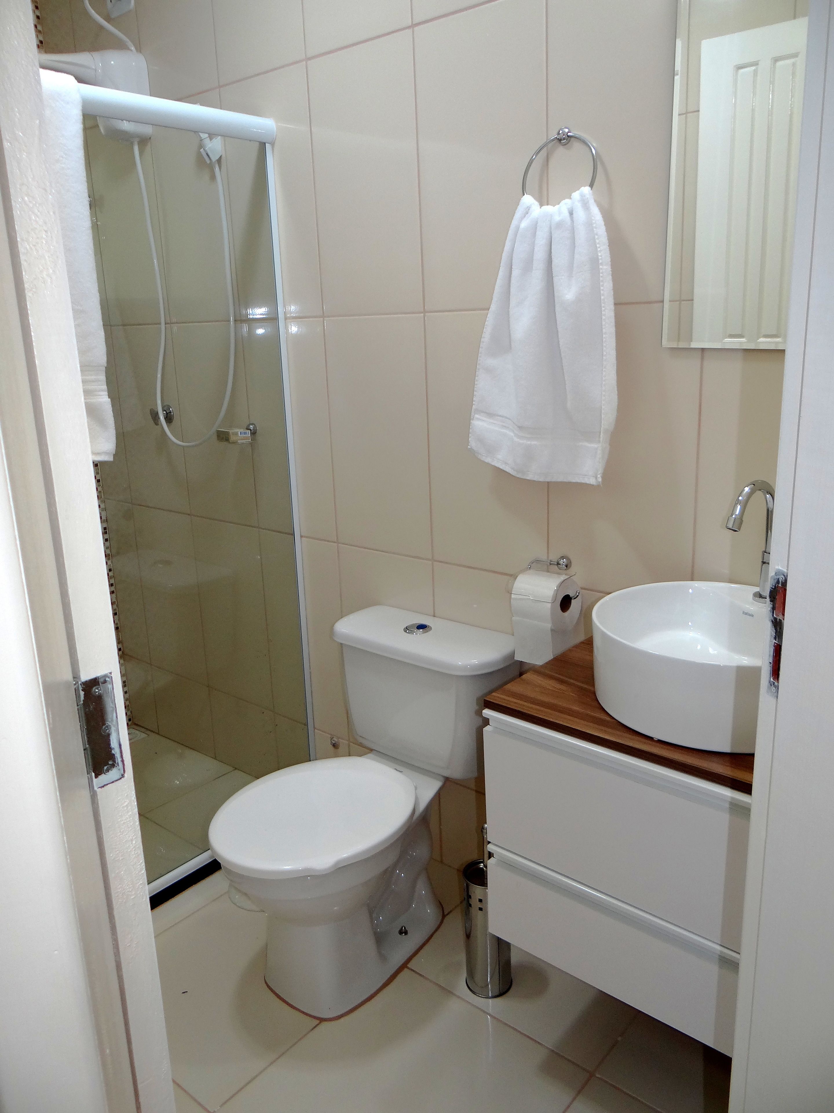 A bathroom with a toilet, a sink, a shower, and a towel hanging on the wall.
