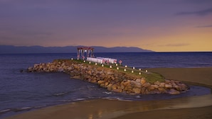 A beachside wedding setup with a covered area and tables arranged for guests.