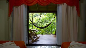 A room with a hammock, a wooden rocking chair, and a bed with white bedding. - Hotel Catarata Río Celeste (Katira)