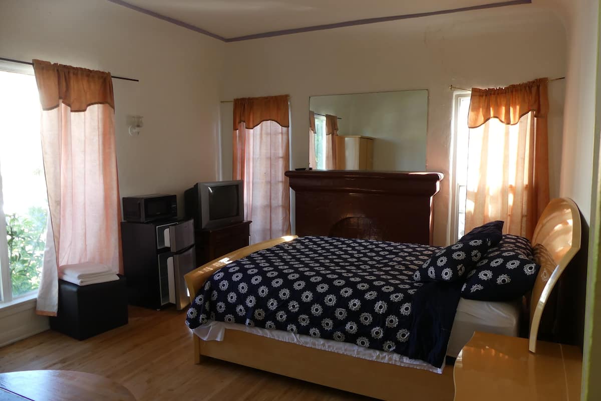 Ein Schlafzimmer mit Bett, Fernseher, Kommode und Spiegel.