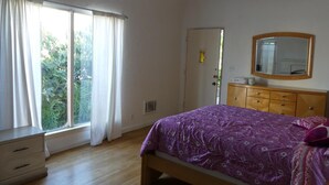 Une chambre à coucher comprenant un lit, une commode, un miroir et une porte donnant sur un balcon.
