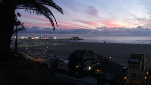 Une vue côtière avec une plage, une jetée et des bâtiments au premier plan.