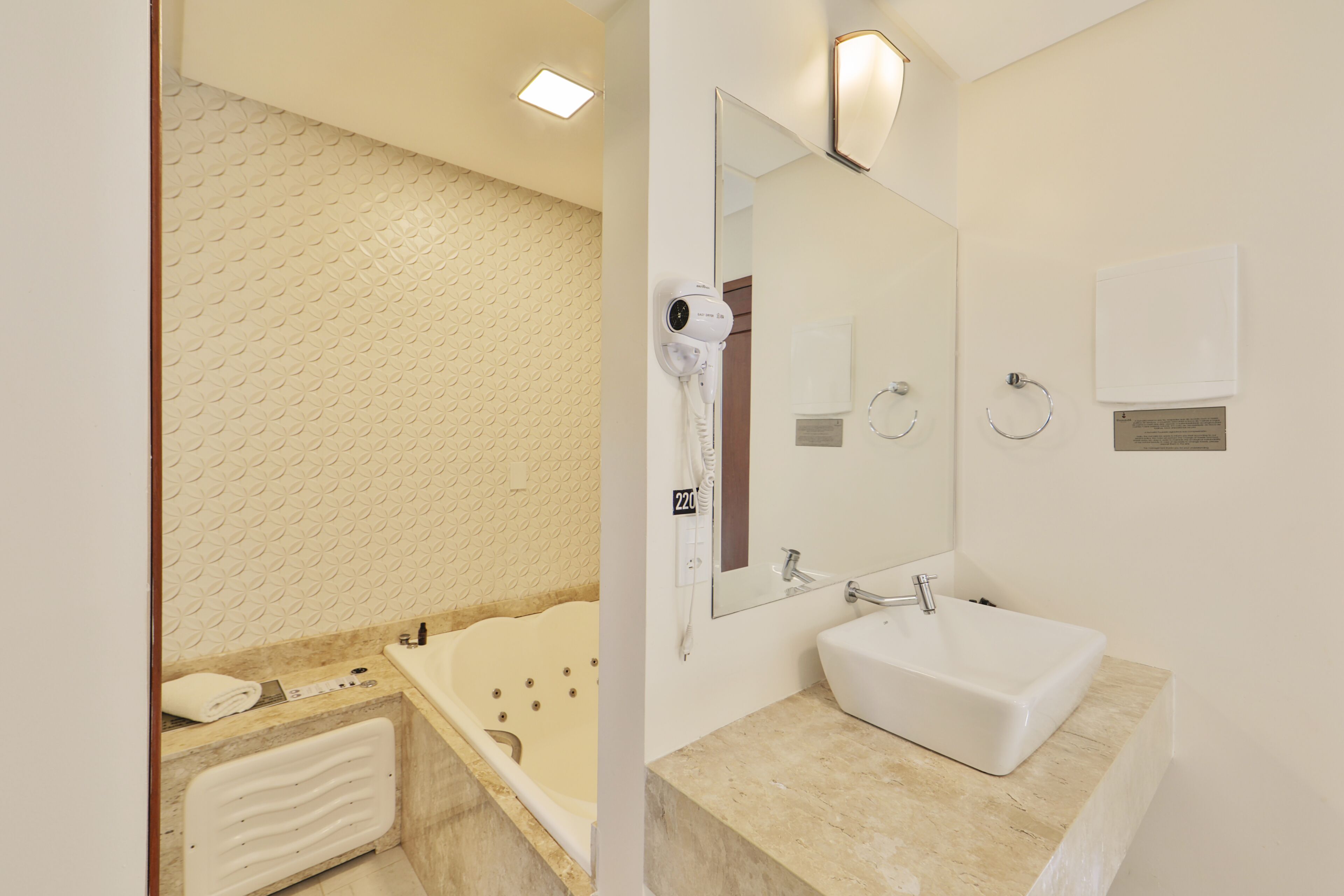 A modern bathroom with a bathtub, a sink, a mirror, and a towel rack.