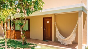 A hotel entrance with a wooden door marked '17', a hammock, and a small garden area with a palm tree. - Pousada Humaitá (Japaratinga)