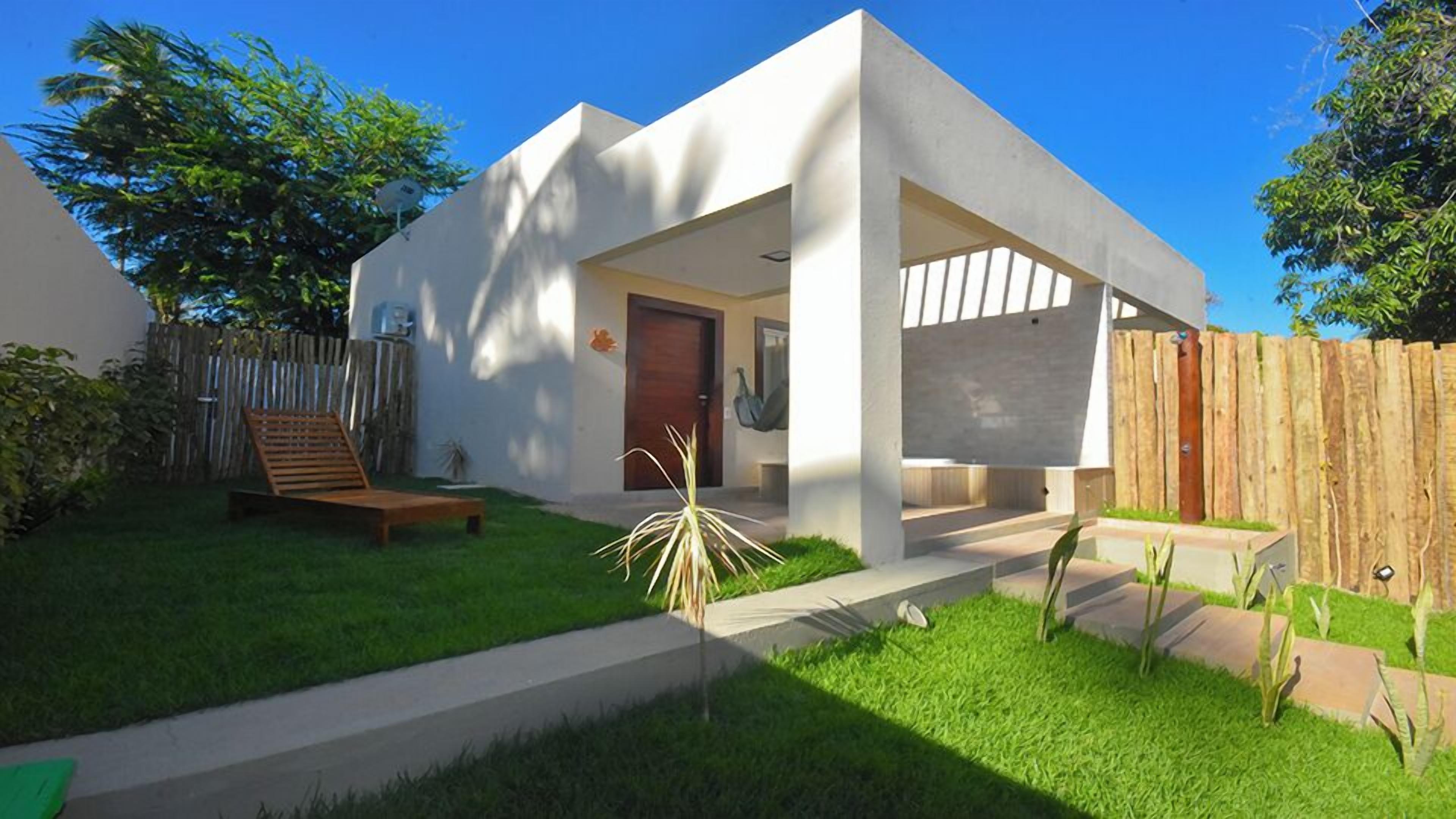 Une maison moderne dotée d’un patio couvert, d’une terrasse en bois et d’un jardin clôturé.