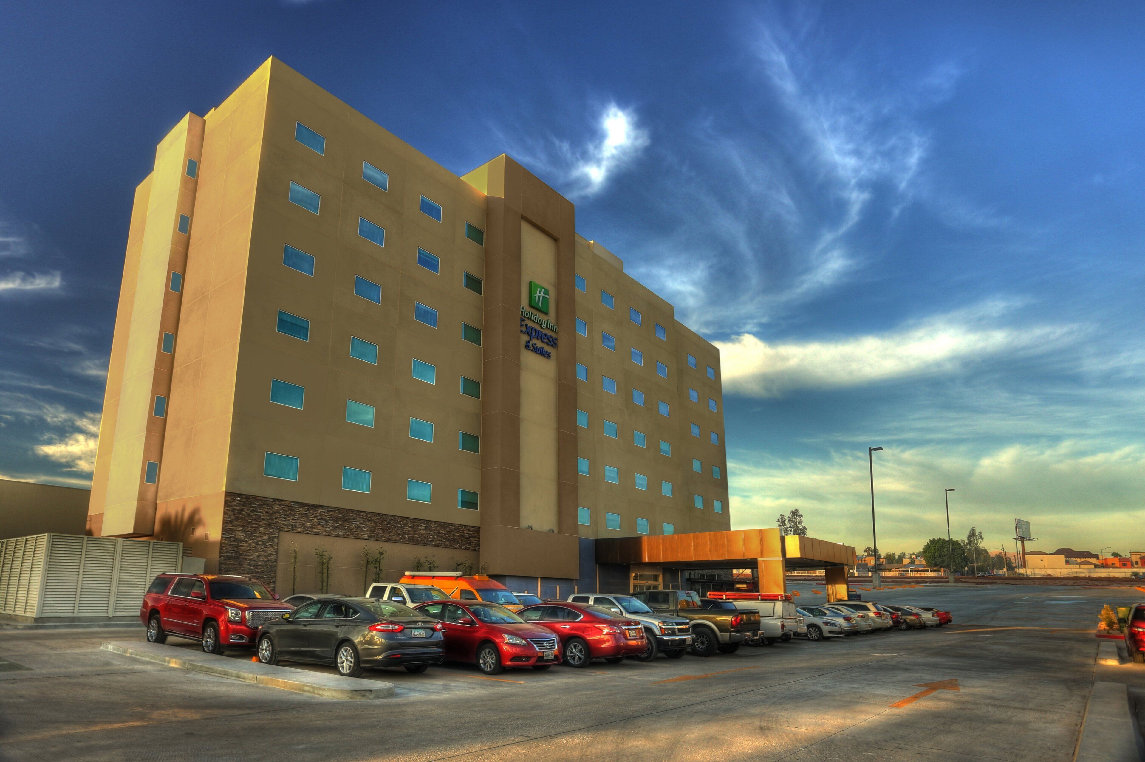 Edificio de Holiday Inn Express con un estacionamiento lleno de coches.