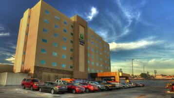 Edificio de Holiday Inn Express con un estacionamiento lleno de coches.