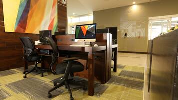 Um espaço de escritório moderno com uma mesa, cadeiras e um monitor de computador.