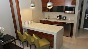 A modern kitchen with a central island, bar stools, wooden cabinets, stainless steel appliances, and pendant lighting. - Holiday Inn Express & Suites Mexicali by IHG (Mexicali)