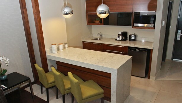 A modern kitchen with a central island, bar stools, wooden cabinets, stainless steel appliances, and pendant lighting. - Holiday Inn Express & Suites Mexicali by IHG (Mexicali)