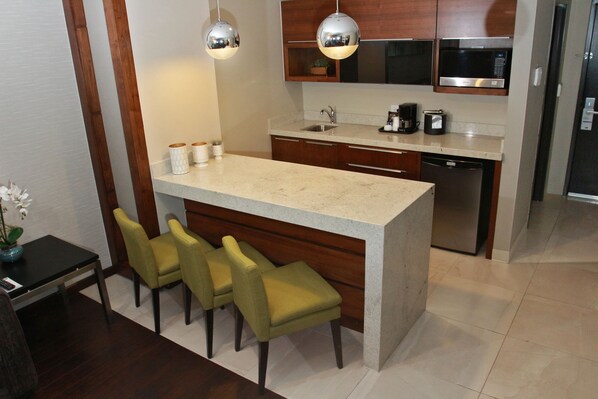 A modern kitchen with a central island, bar stools, wooden cabinets, stainless steel appliances, and pendant lighting. - Holiday Inn Express & Suites Mexicali by IHG (Mexicali)