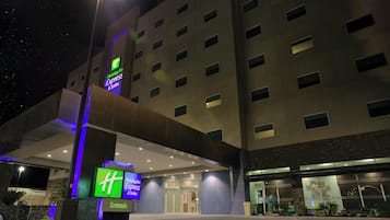 Der Eingang eines Holiday Inn Express & Suites Hotels mit modernem Design, erkennbar am großen 'Holiday Inn Express & Suites' Schild und der gut beleuchteten Fassade.