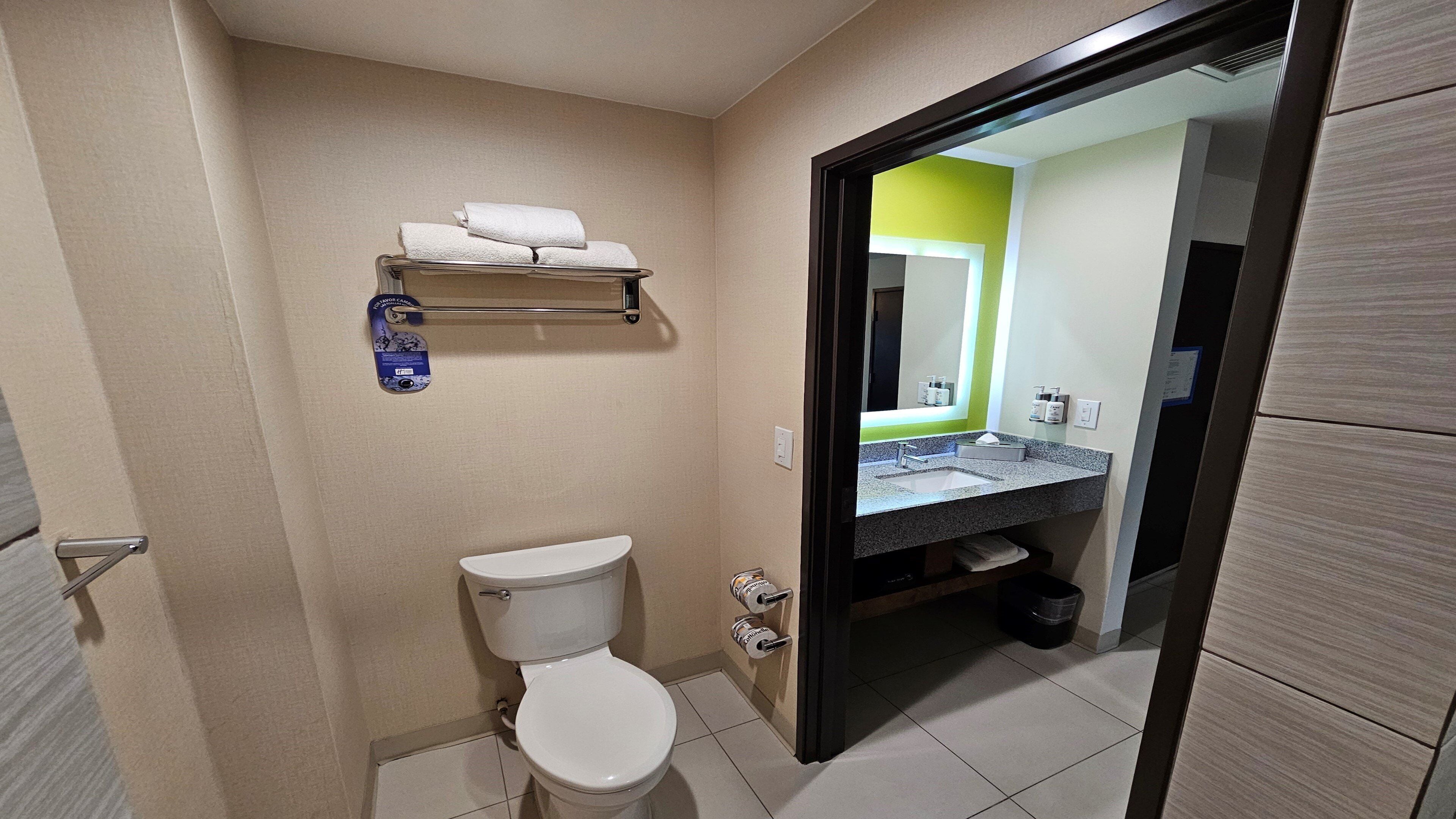 Une salle de bain comprenant des toilettes, un lavabo avec un miroir et un porte-serviettes.