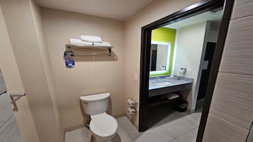 Une salle de bain comprenant des toilettes, un lavabo avec un miroir et un porte-serviettes.