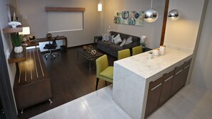 A modern kitchen with a marble countertop, a dining area with a table and chairs, and a living area with a sofa and decorative pillows. - Holiday Inn Express & Suites Mexicali by IHG (Mexicali)