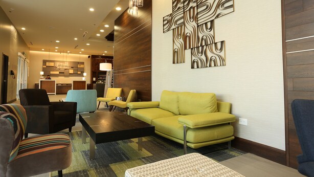 A modern living room with a sofa, armchairs, a coffee table, and a decorative wall piece. - Holiday Inn Express & Suites Mexicali by IHG (Mexicali)