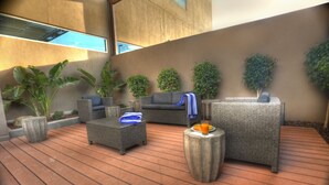 A modern outdoor seating area with wicker furniture, potted plants, and a wooden deck. - Holiday Inn Express & Suites Mexicali by IHG (Mexicali)
