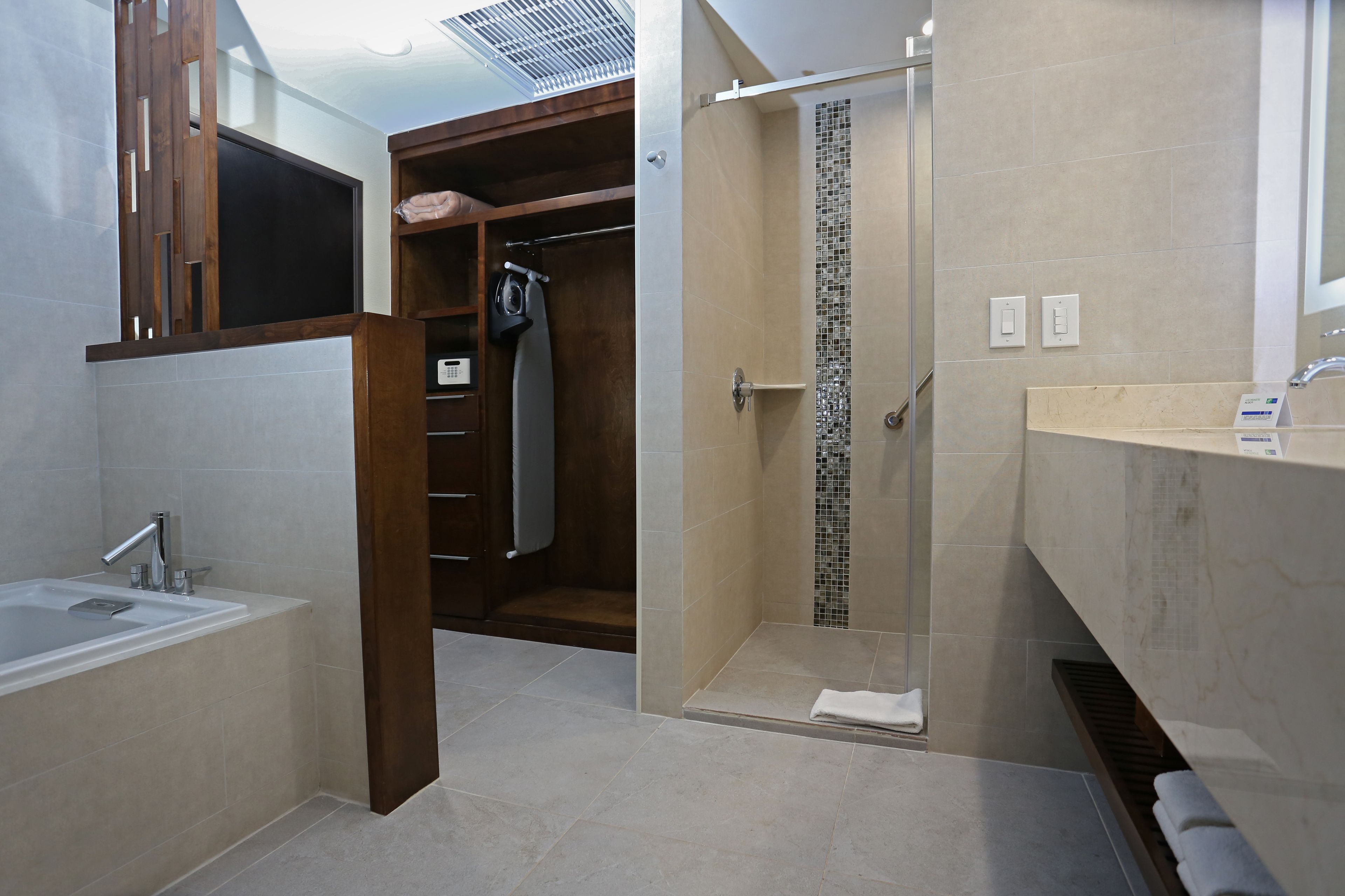 A modern bathroom with a bathtub, shower, and walk-in closet.