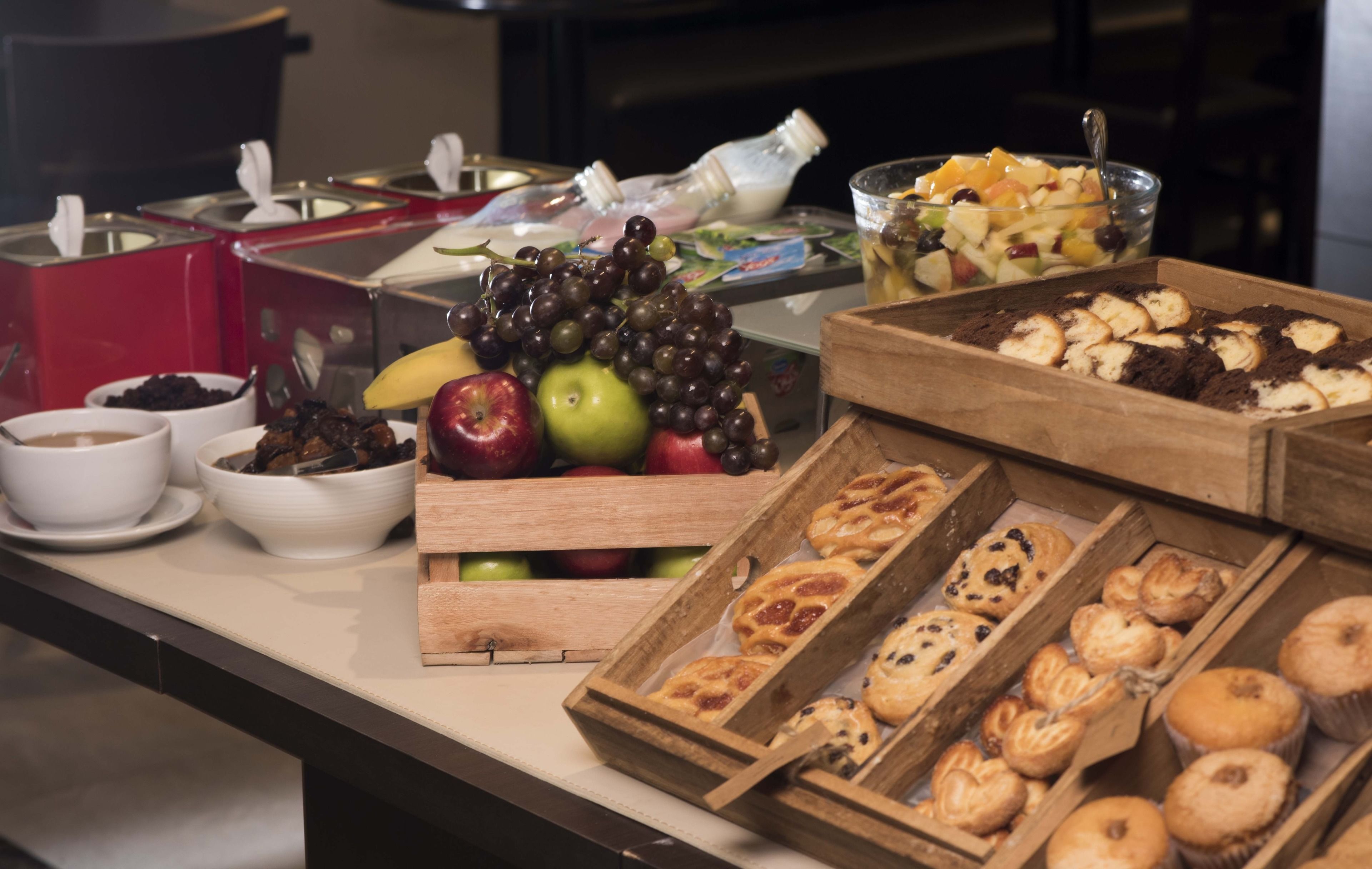 Ein Buffet mit verschiedenen Speisen, darunter Obst, Gebäck und Getränke.