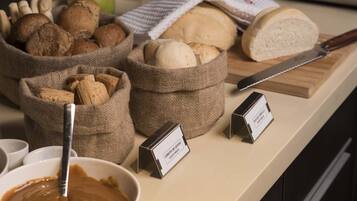 Una encimera de cocina con diferentes panes, un cuchillo y un bol de crema.
