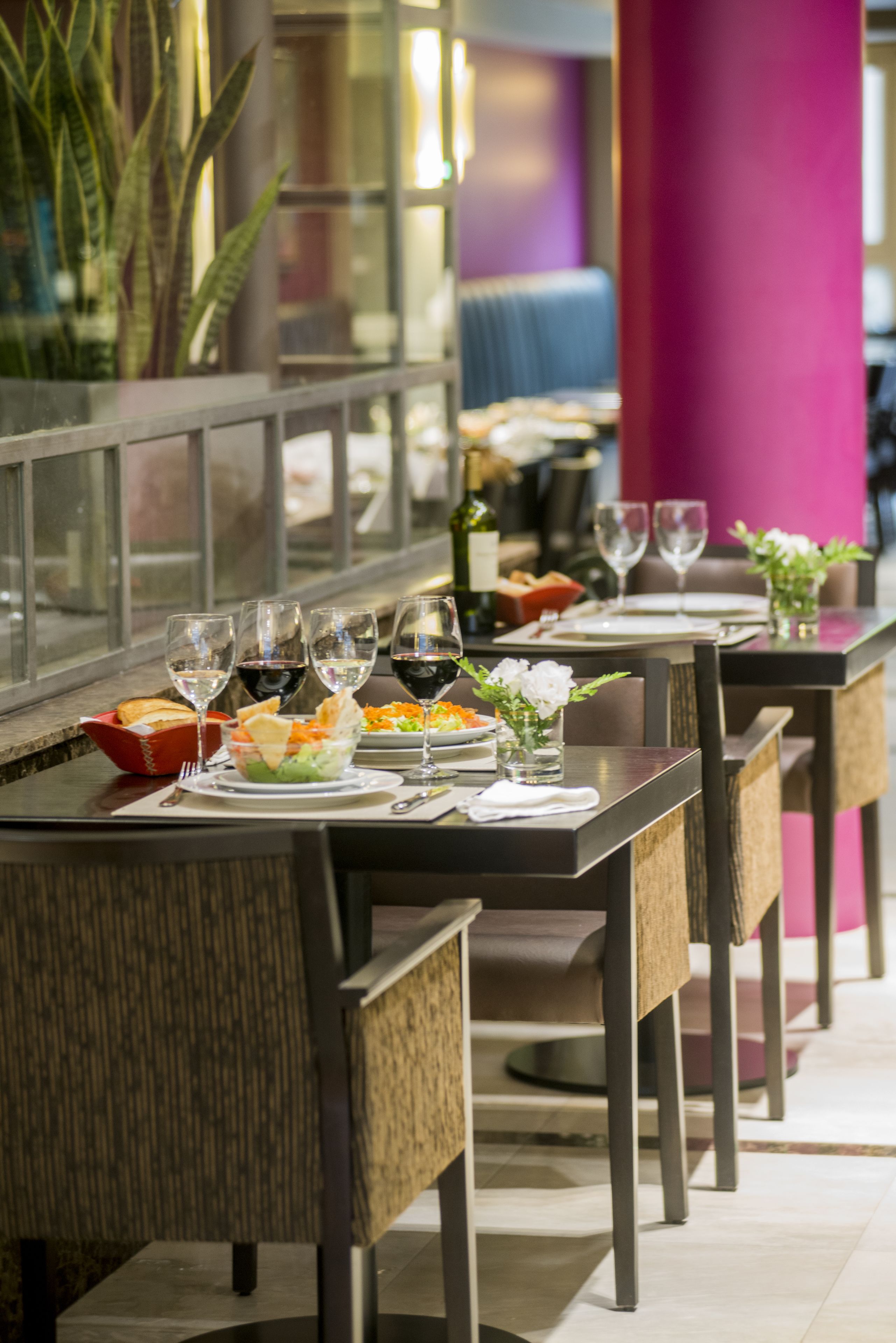 Ein Restaurant mit einem langen Esstisch, gedeckt mit Geschirr, Weingläsern und einem Blumenstrauß.
