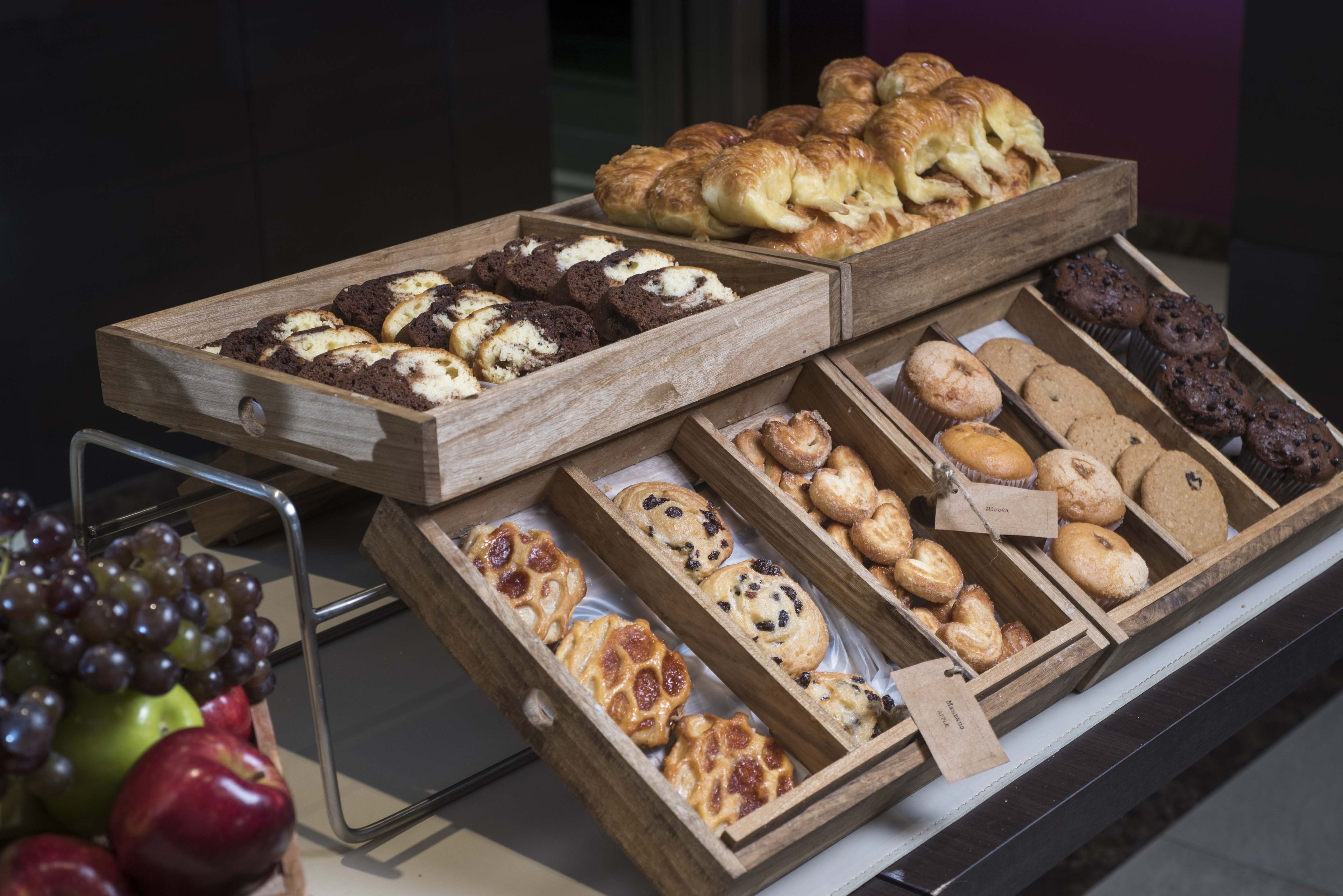 A display of assorted baked goods in wooden trays, including pastries and cookies.