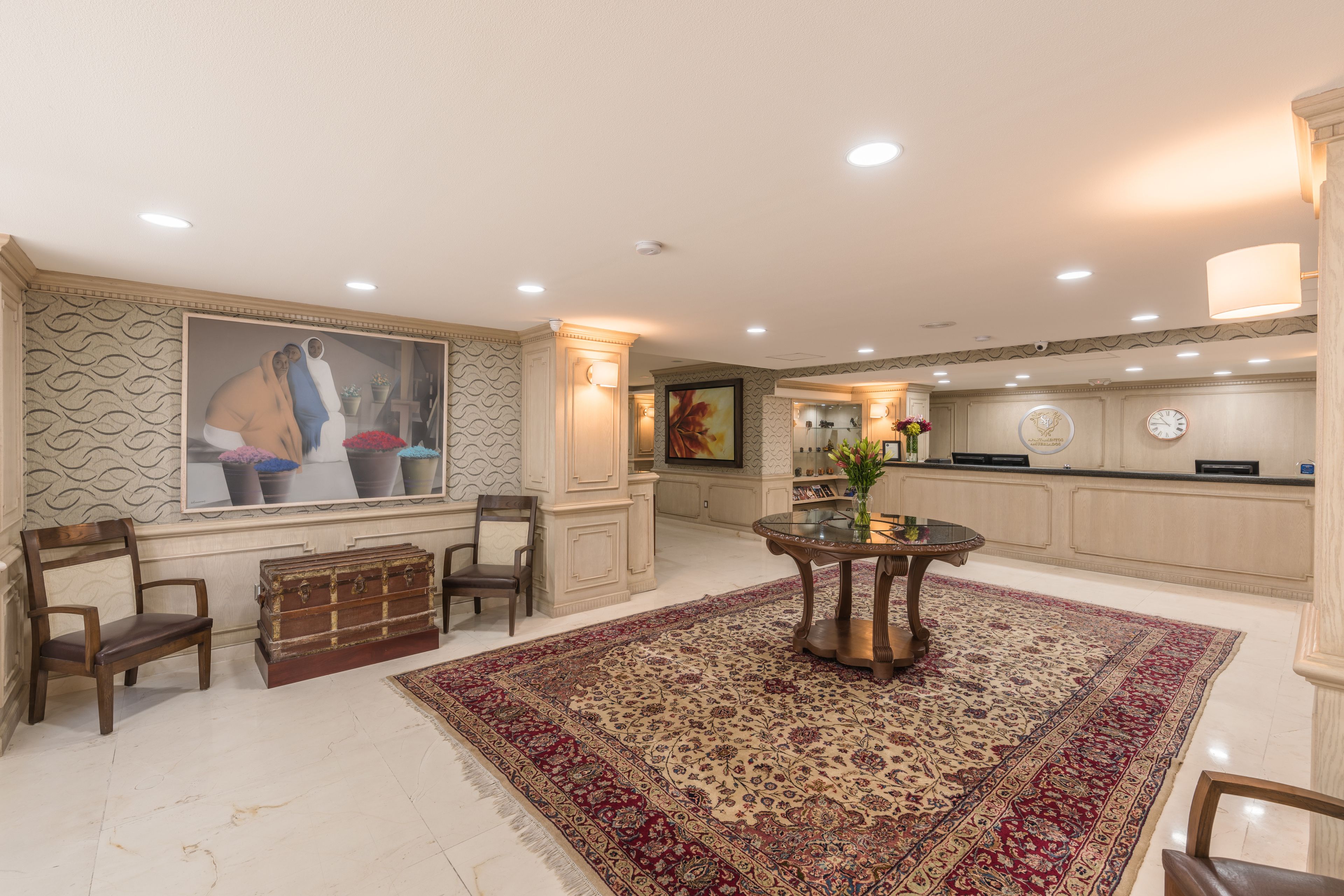 Amplia sala de estar con un tapete grande, muebles de madera y un cuadro en la pared.