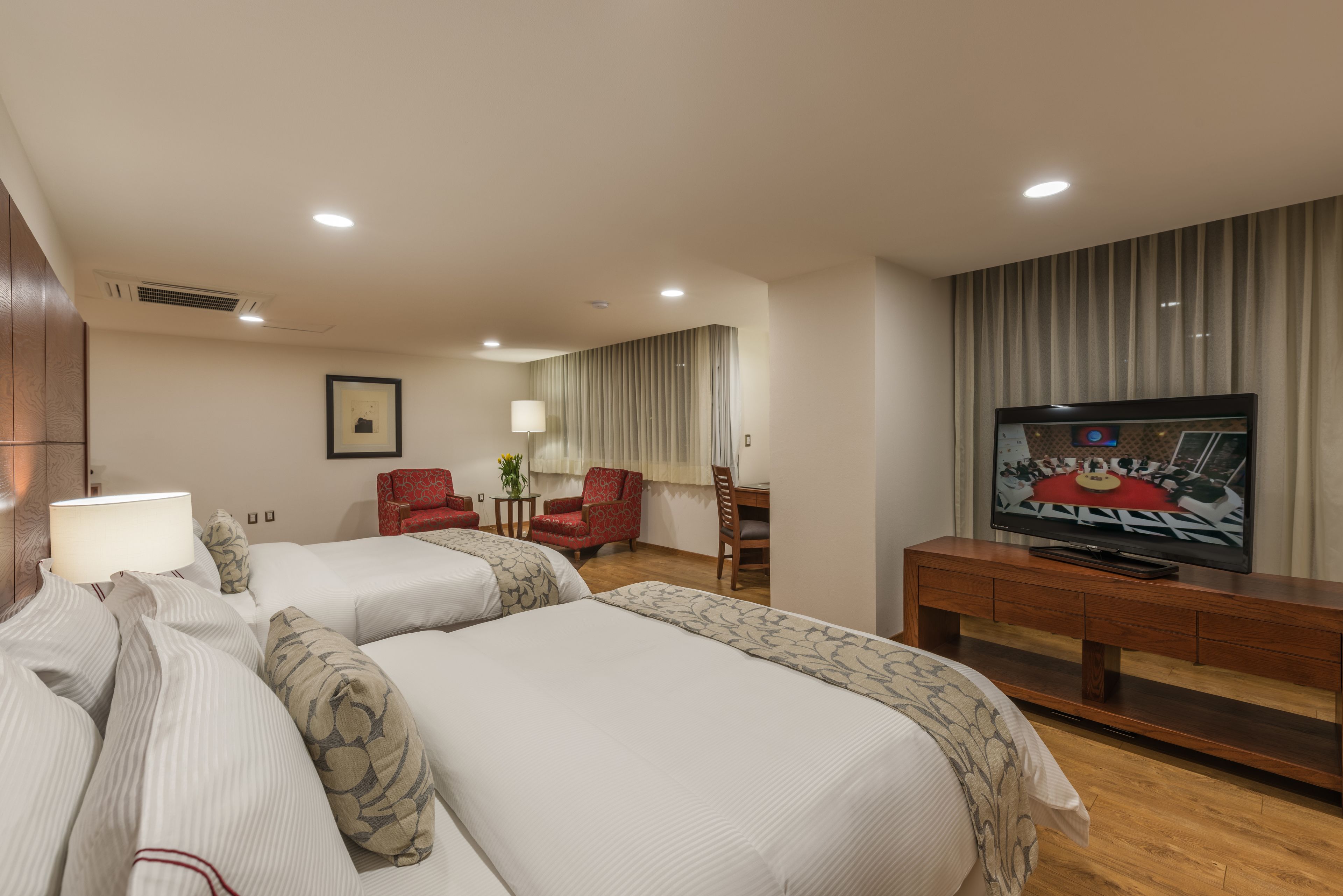 Una habitación de hotel con dos camas, televisión, escritorio y una silla.