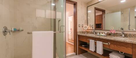 Un baño moderno con cabina de ducha de vidrio, tocador con un espejo grande y un armario de madera.