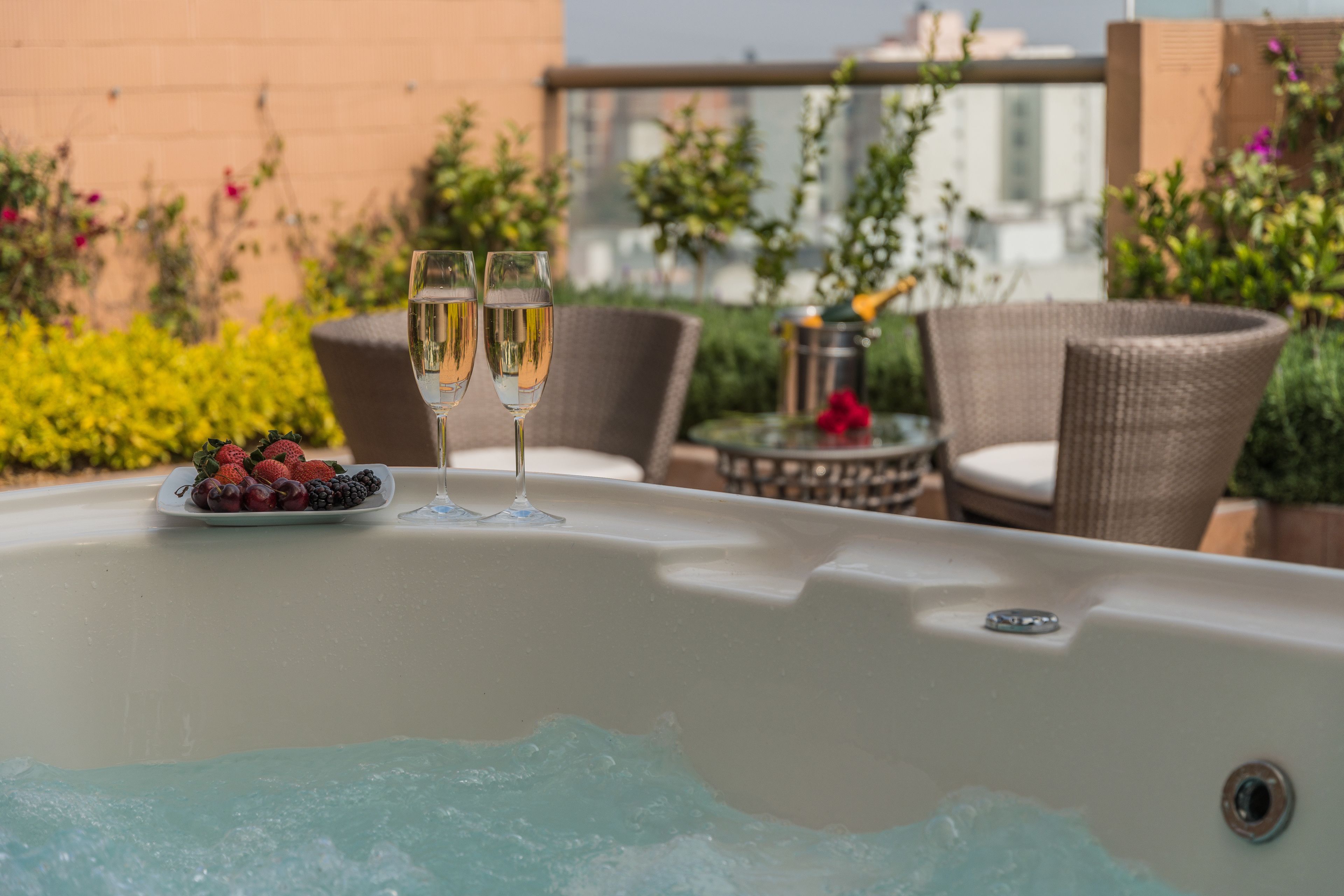 Ett bubbelbad med två glas champagne och en tallrik med frukt.