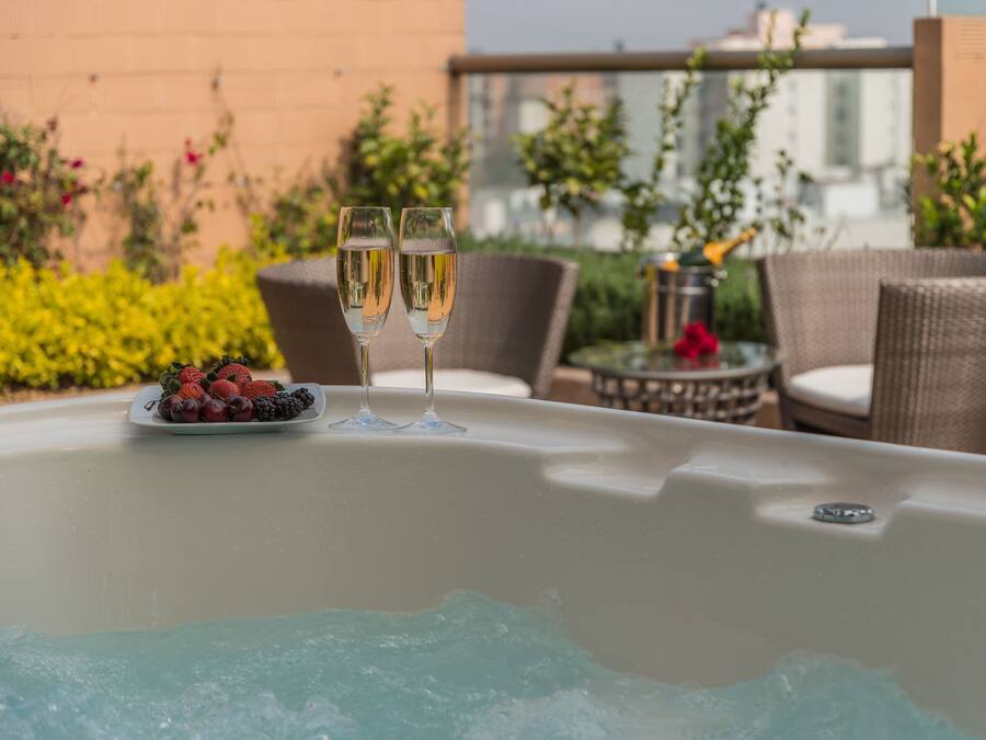 A hot tub with two glasses of champagne and a plate of fruit.