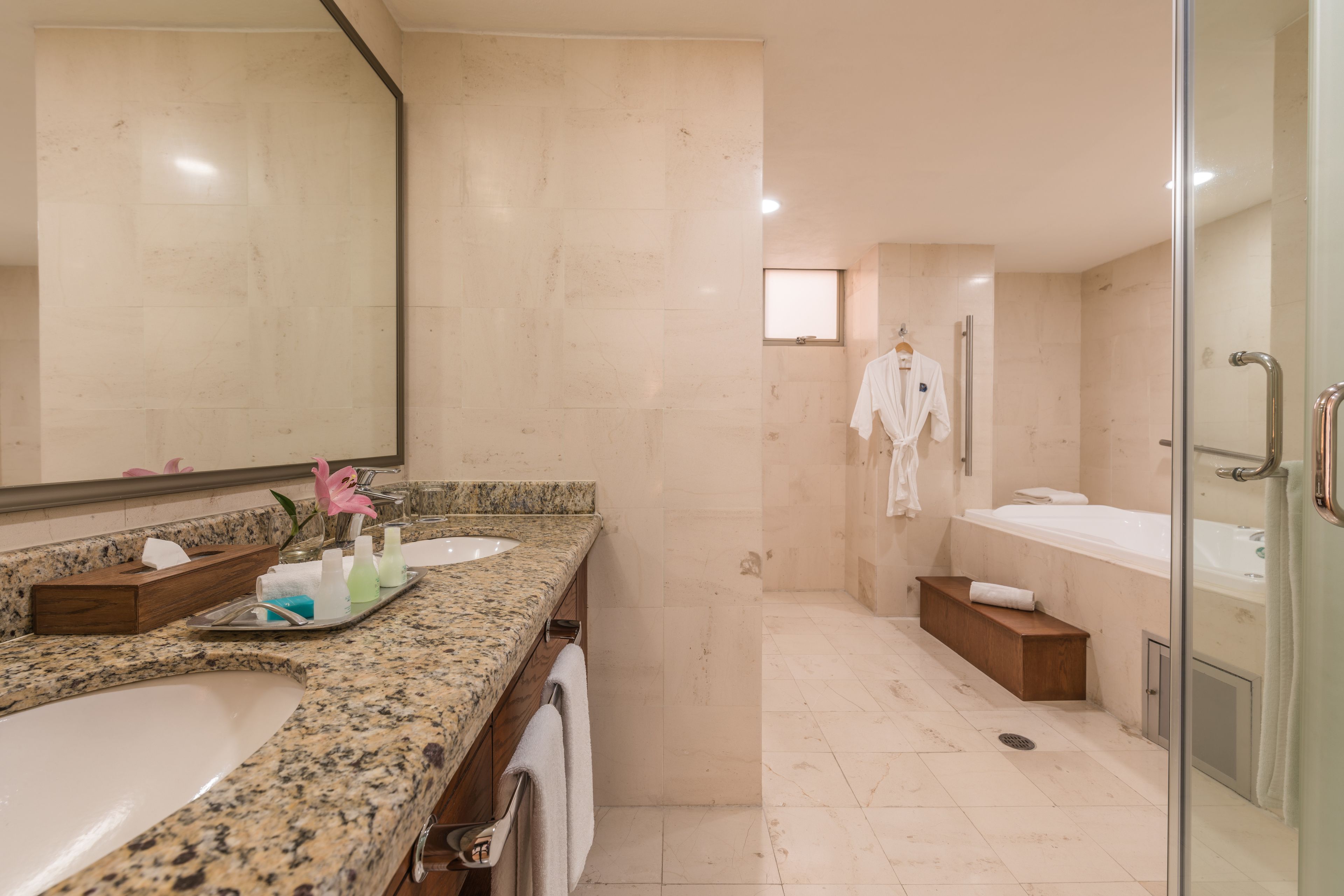 Een moderne badkamer met een granieten aanrechtblad, een grote spiegel, een douche en een bad.