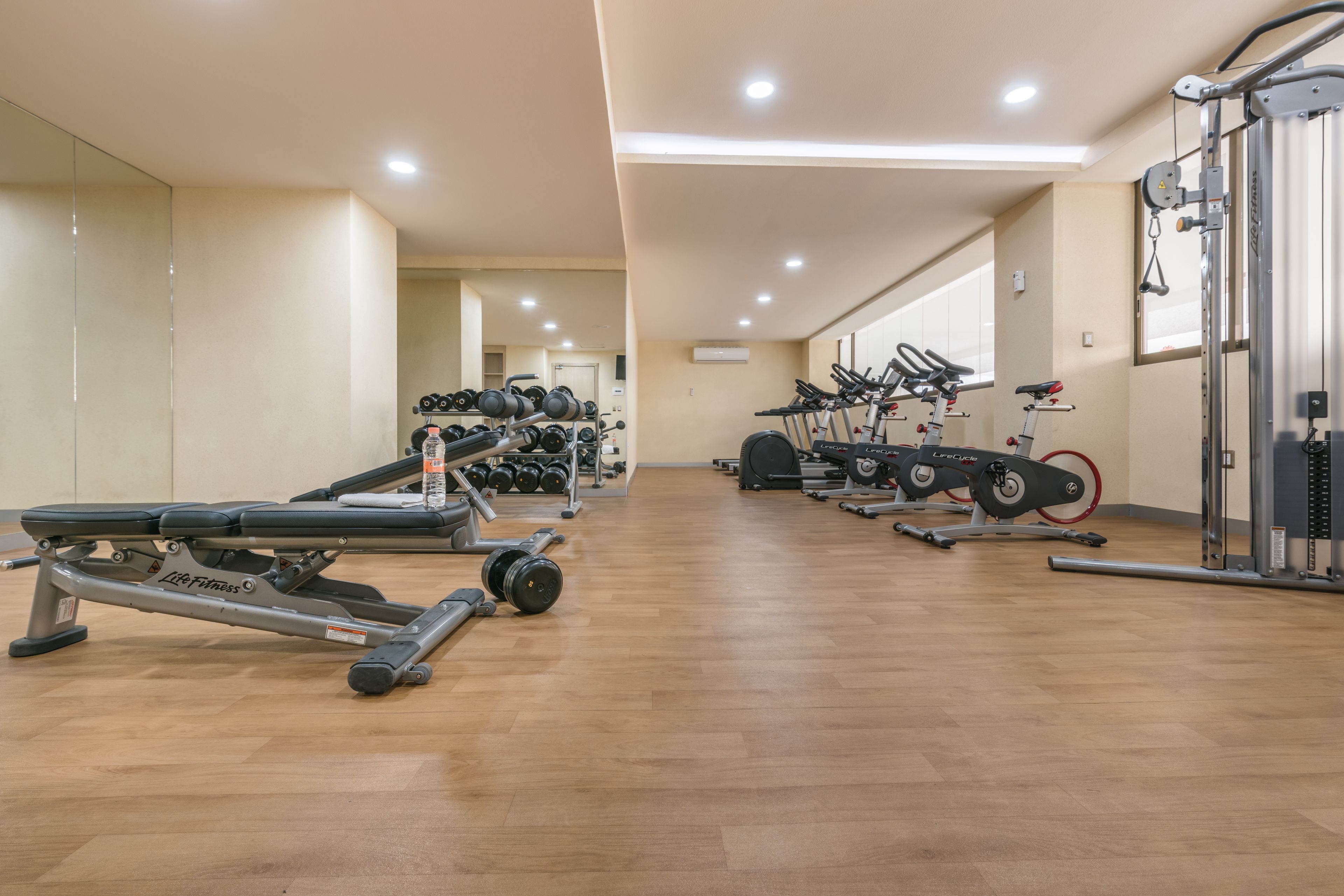 A gym with exercise equipment, including treadmills, weight machines, and a rowing machine.