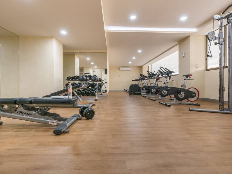 A gym with exercise equipment, including treadmills, weight machines, and a rowing machine.