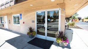A building entrance with a glass door, a handicap parking sign, and potted plants.