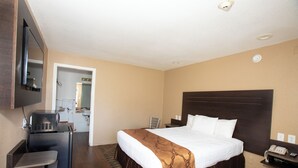 A hotel room with a bed, a desk with a telephone, and a TV mounted on the wall.