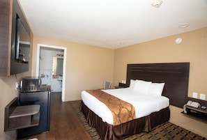 A hotel room with a bed, a desk with a telephone, and a TV mounted on the wall.