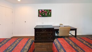 A hotel room with two beds, a dresser, a desk, and a television mounted on the wall.