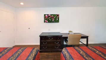 Habitación de hotel con dos camas, un aparador, un escritorio y un televisor montado en la pared.
